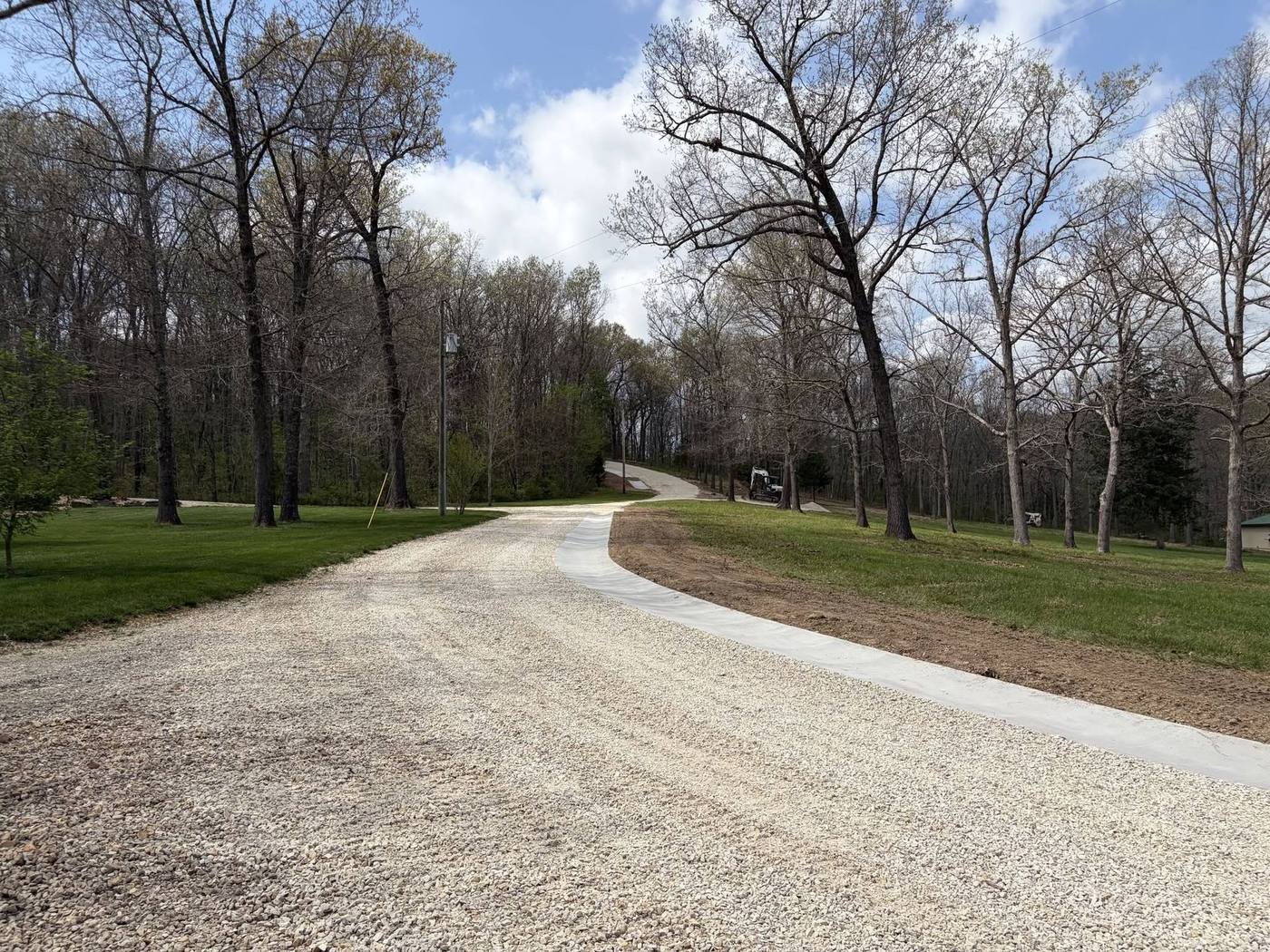 Ribbon curb following a gravel drive up through the trees