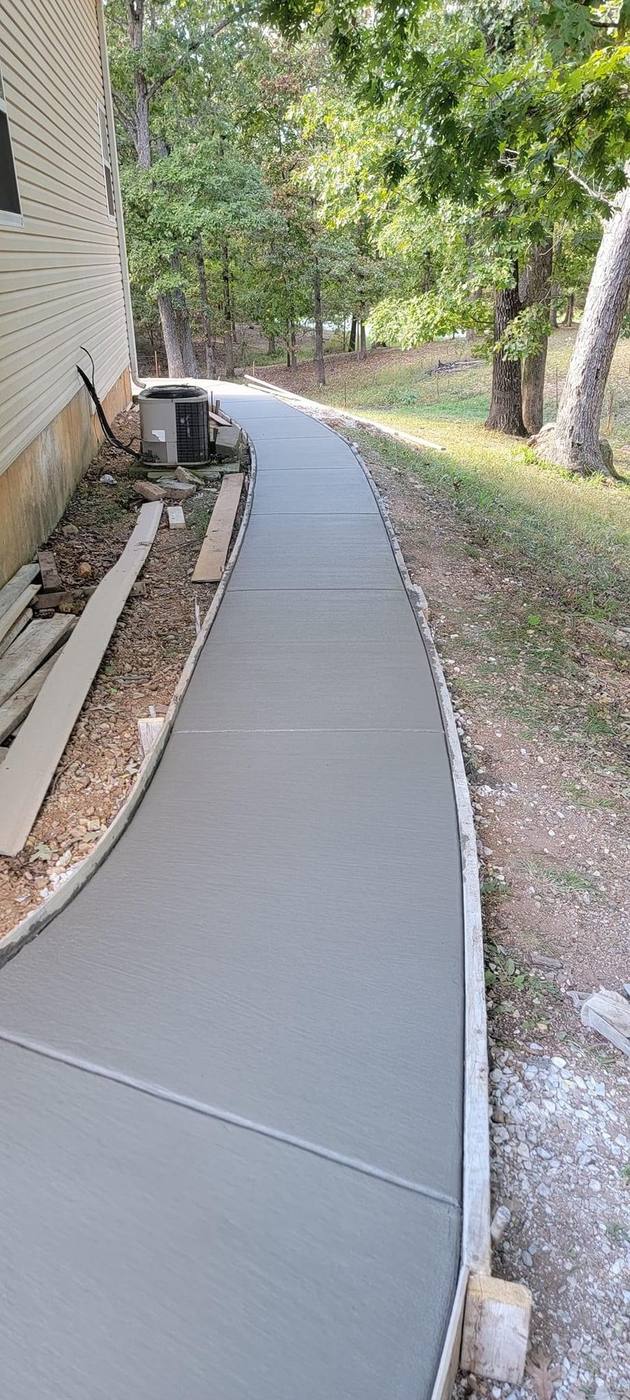 Long curved fresh-poured sidewalk running beside a house